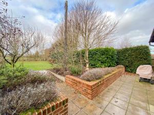 a garden with a brick wall and some bushes at Polly's Yard Dennington Suffolk in Dennington
