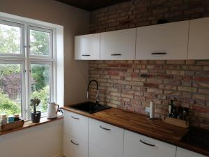 una cocina con armarios blancos y una pared de ladrillo en Cozy Villa-Apartment - Close to Aalborg center - Free citybikes and parking en Aalborg