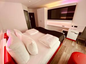 DORMERO Hotel Bretten في بريتن: غرفة نوم مع سرير وتلفزيون بشاشة مسطحة
