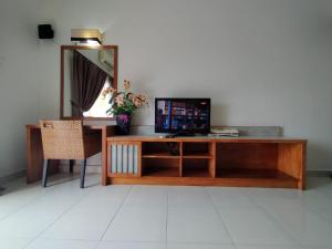 a desk with a television and a mirror and a chair at Buluh Inn @ Gold Coast Morib in Banting