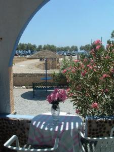 ペリヴォロスにあるDARZENTA ATHINA APARTMENTS Perivolosのピンクの花瓶を飾ったテーブル