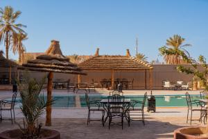 a patio with tables and chairs next to a pool at Kasbah Hotel Ziz Palace Rissani in Rissani