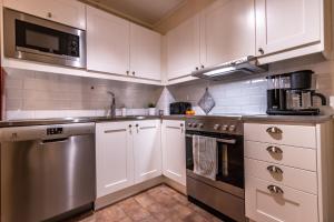 a kitchen with white cabinets and stainless steel appliances at Vasabyn Fjällhem - Lindvallen - Ski in Ski Out in Sälen