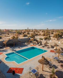 a swimming pool with chairs and umbrellas in the desert at Kasbah Hotel Ziz Palace Rissani in Rissani