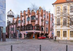 a large building with a red car parked in front of it at Limehome Magdeburg Breiter Weg in Magdeburg