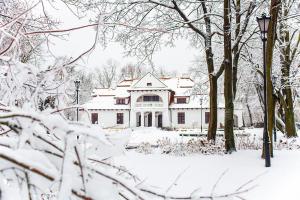 een huis bedekt met sneeuw in een park bij Rezydencja Dwór Polski in Bełchatów