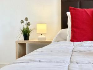 サロウにあるApartamentos Zaragozaのベッド(赤い枕付)、テーブル(ランプ付)