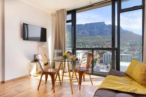 a living room with a table and chairs and a large window at Urban Oasis At The Four Seasons in Cape Town
