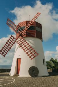 a red and white windmill sitting on the beach at Moinho das Feteiras in Feteiras