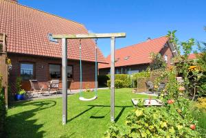 een tuin met een schommel en een huis bij Ferienwohnungen Haus Meeresleuchten in Bensersiel