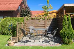 een patio met een tafel en stoelen in de achtertuin bij Ferienwohnungen Haus Meeresleuchten in Bensersiel