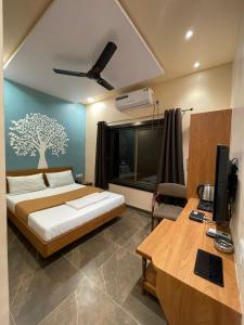 a bedroom with a bed and a desk with a television at Hotel Vardhan in Silvassa