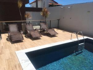 a group of chairs sitting next to a swimming pool at Praia Bela, vista mar. Novo! in Pitimbu