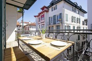 - une table en bois sur un balcon avec des bâtiments dans l'établissement Appartement Gambetta, à Saint-Jean-de-Luz