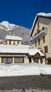 un edificio cubierto de nieve con una montaña en el fondo en Hôtel Restaurant de la poste, en Saint-Colomban-des-Villards