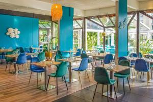 un restaurant avec des murs bleus et des tables et des chaises en bois dans l'établissement Novotel Marseille Est Porte d'Aubagne, à Marseille