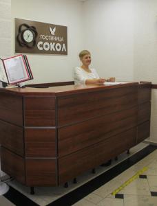 a woman is sitting at a reception desk at Sokol Hotel in Sochi