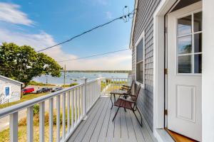 a porch with a bench and a door with a view of the water at Bella Luna in Falmouth