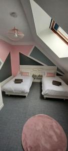 a room with two beds and a pink wall at Gîte "La bulle de Léna" avec petit-déjeuner garage et parking in Flavigny