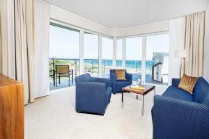 a living room with blue chairs and a view of the ocean at The Grand in Ahrenshoop