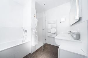 a white bathroom with a sink and a mirror at The Grand in Ahrenshoop