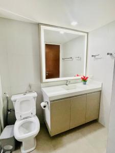 een badkamer met een toilet, een wastafel en een spiegel bij Apartamento Aquaville Resort in Aquiraz