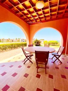 patio ze stołem i krzesłami oraz 2 dużymi oknami w obiekcie FabbricaCasa Sea Front Villa, Oriental Coast w Marsa Alam