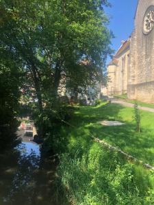 eine Kirche mit einem Baum neben einem Fluss in der Unterkunft Aux portes du Val d'Amour 