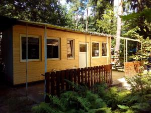 eine kleine Hütte im Wald mit einem Holzzaun in der Unterkunft Ferienbungalow auf FKK Waldcampingplatz am See 