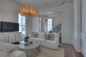 un soggiorno con mobili bianchi e lampadario pendente di The White House Galveston a Galveston