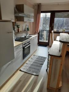 cocina con armarios blancos, fregadero y ventana en Ferienwohnung Waldblick, en Hallenberg