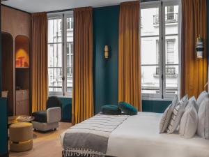 a bedroom with a bed with blue walls and windows at Dandy Hotel in Paris +92 photos