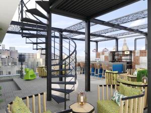 a rooftop patio with a spiral staircase and chairs at Barceló Budapest in Budapest