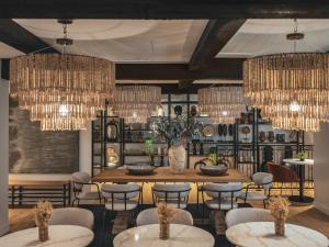 a dining room with a table and chairs and chandeliers at Maisons du Monde Hôtel & Suites - La Rochelle Vieux Port in La Rochelle