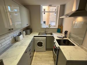 a kitchen with a sink and a washing machine at Red Gables - Ground Floor in Carlisle