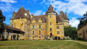 ein altes Schloss mit einem Grasfeld davor in der Unterkunft Maison de vacances en Dordogne in Lanquais