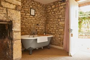 a bath tub in a room with a stone wall at The Lamb Inn in Shipton under Wychwood