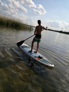 a man standing on a paddle board in the water at Ferienhaus Scandia am See in Warnitz