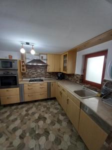 cocina con armarios de madera, fregadero y ventana en Casa David, en Gârda de Sus