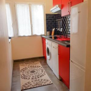 cocina con armarios rojos, lavadora y secadora en VILLA REIALA Chaville, en Chaville