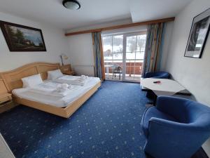 um quarto de hotel com uma cama e uma cadeira em Ferienhotel Alpenhof em Aurach bei Kitzbuhel