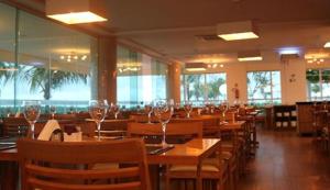 um restaurante com mesas e cadeiras de madeira e copos de vinho em Salinas Park Resort em Salinópolis