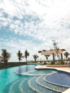 uma piscina com palmeiras e um céu nublado em Salinas Park Resort em Salinópolis