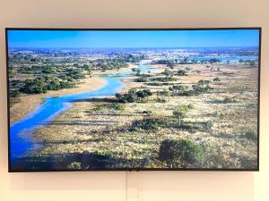 a flat screen tv hanging on a wall with a river at FONTAINE ROUGE STREET Marne la Vallée Disneyland Paris Outlet Mode And luxury Village Val d'europe FREE PARKING in Chessy