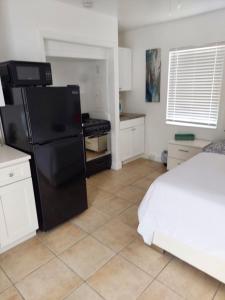 a kitchen with a black refrigerator and a bed at Singer Island Inn Studio/ Walk to the Beach in West Palm Beach