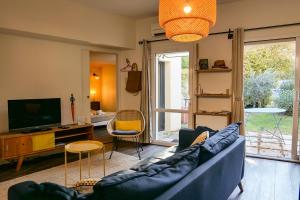 a living room with a blue couch and a tv at Villa Joseph in Saint-Paul-Trois-Châteaux