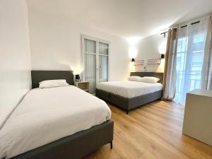two beds in a room with white walls and wooden floors at FONTAINE ROUGE STREET Marne la Vallée Disneyland Paris Outlet Mode And luxury Village Val d'europe FREE PARKING in Chessy