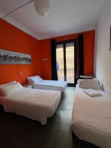 3 camas en una habitación con pared de color naranja en Pensión Arosa, en Barcelona