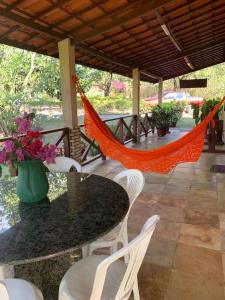 eine Hängematte auf einer Terrasse mit einem Tisch und Stühlen in der Unterkunft Sítio São Gerardo - Aconchegante casa no campo. in Guaramiranga