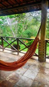 a hammock on a porch with a view of a forest at Sítio São Gerardo - Aconchegante casa no campo. in Guaramiranga